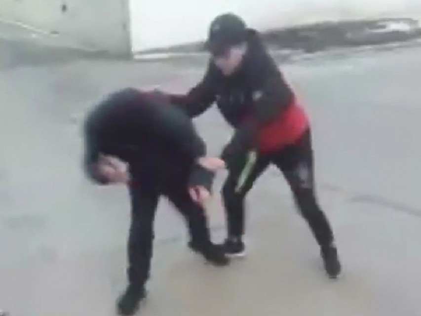 Пока школьница бьет юношу, а тот умоляет ее остановиться, свидетели снимают произошедшее на видео.