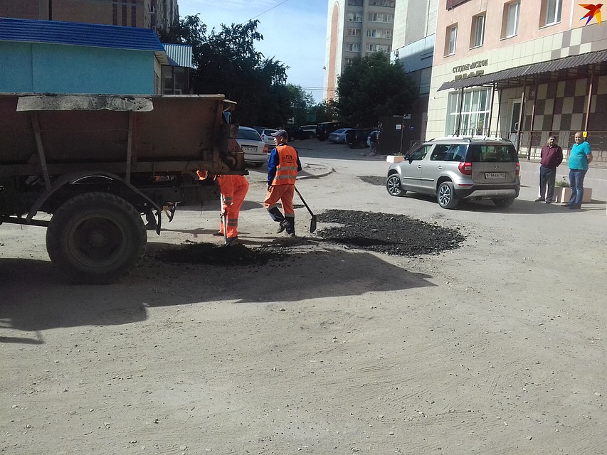 Рабочие засыпают ямы срезанным асфальтом