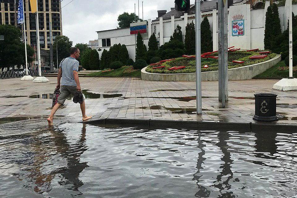 Люди снимают обувь, чтобы перейти глубокие лужи.