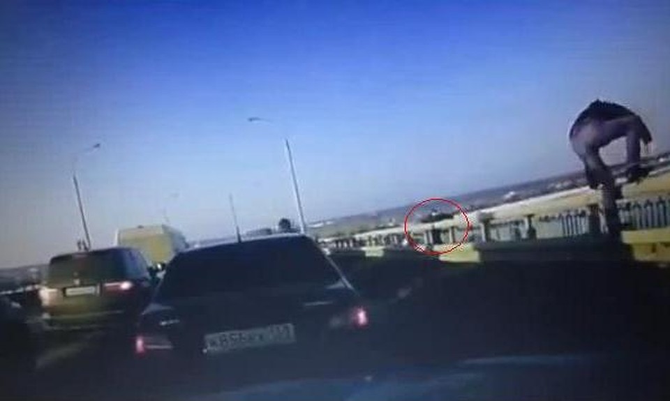 Скрин с видео: прохожий успел поймать женщину (в красном круге), и на помощь ему поспещили водители автомобилей (один из них - мужчина справа на фото).