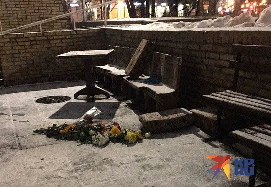 Люди с цветами подходят к храму и кладут букеты на черный незапорошенный след, в котором угадывается фигура человека. Фото: Евгения СУНДУКЯН