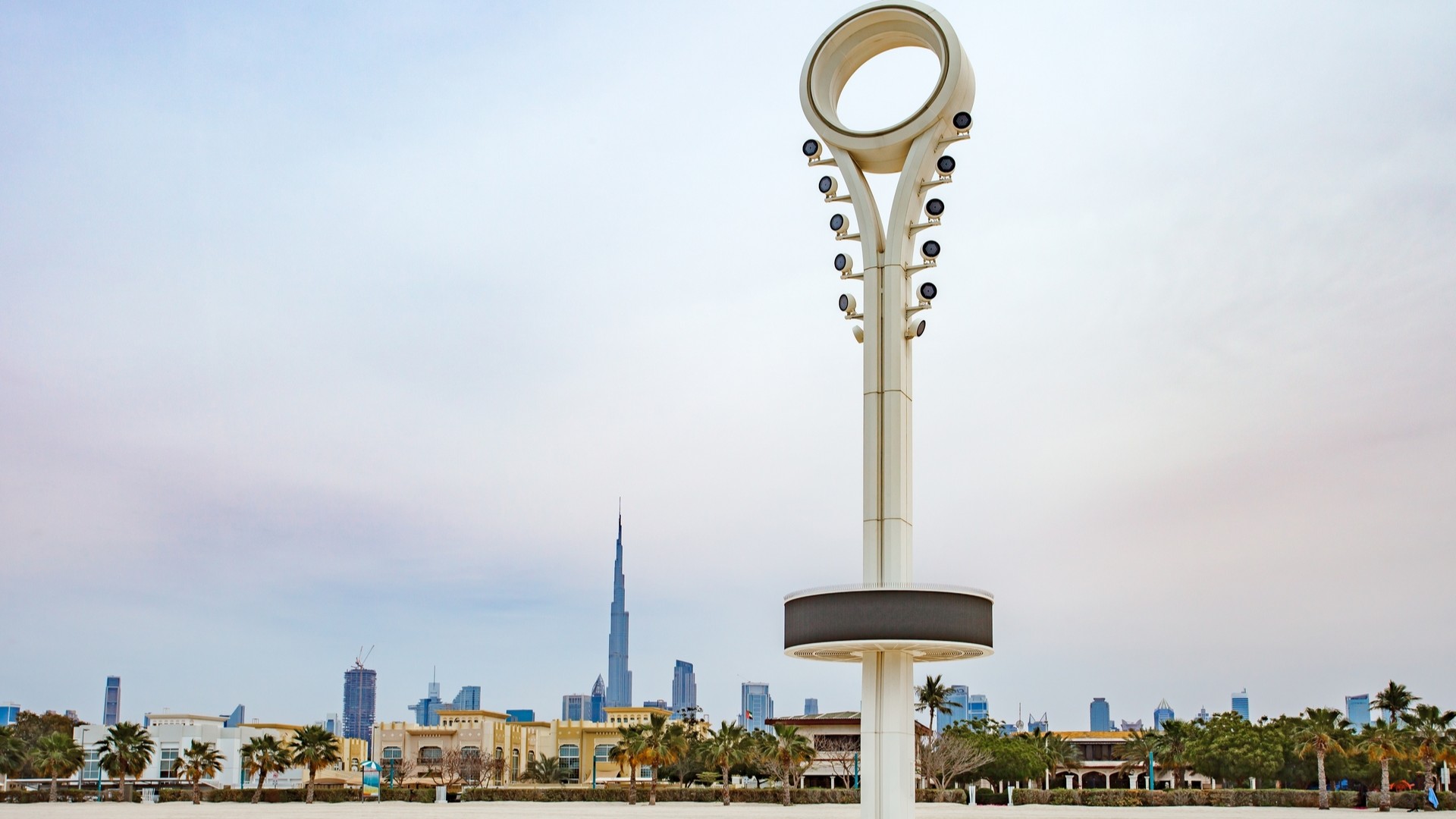 Осветительная мачта на пляже Jumeirah Open Beach и вид на небоскреб Бурдж-Халифа.